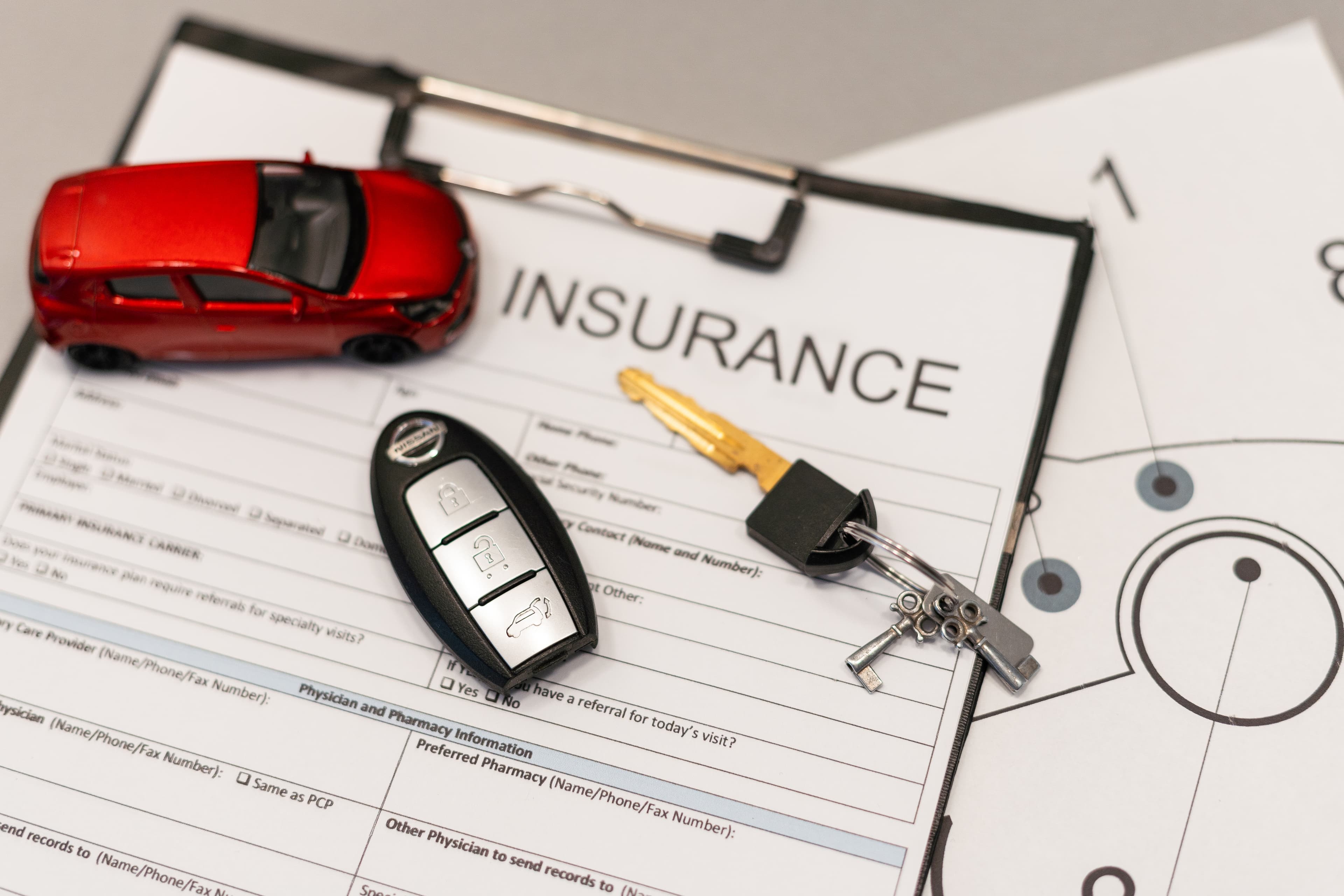 Auto insurance documents with car key and toy car